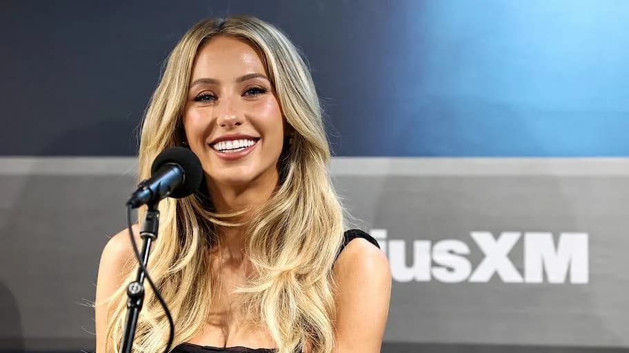 Alix Earle smiling while speaking into a microphone at an event