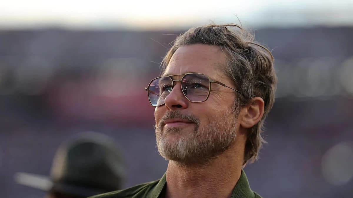 Brad Pitt wearing sunglasses and looking upward at an outdoor event