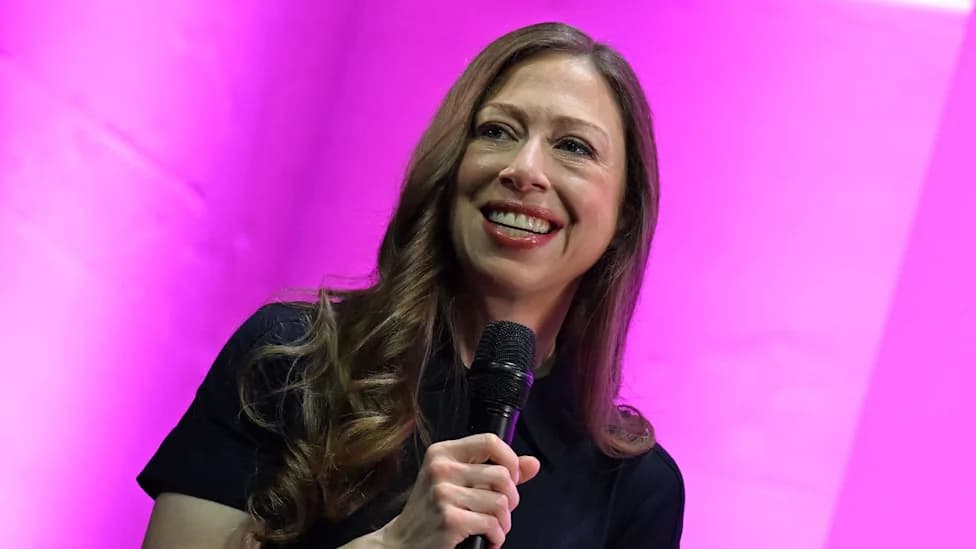 Chelsea Clinton smiling while speaking into a microphone on stage