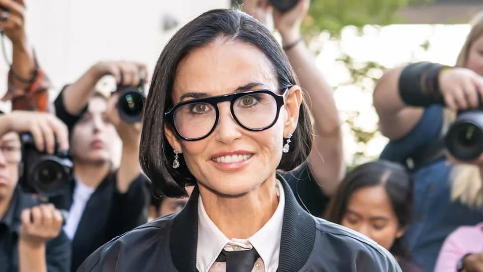 Demi Moore wearing glasses and a black jacket at a fashion week event