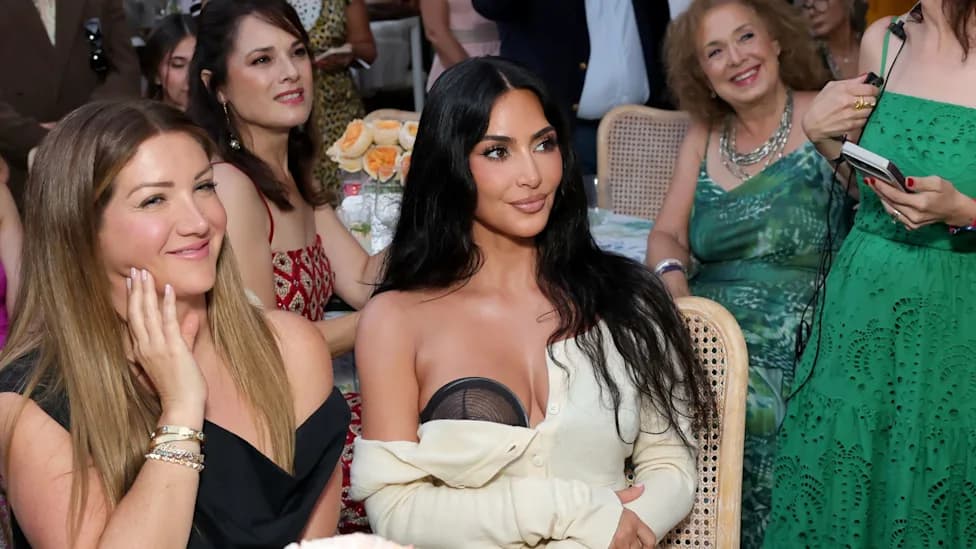 Kim Kardashian seated among guests at an outdoor charity event