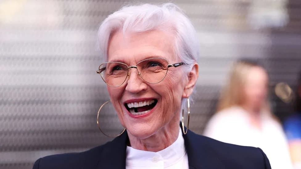 Maye Musk laughing while wearing glasses and hoop earrings