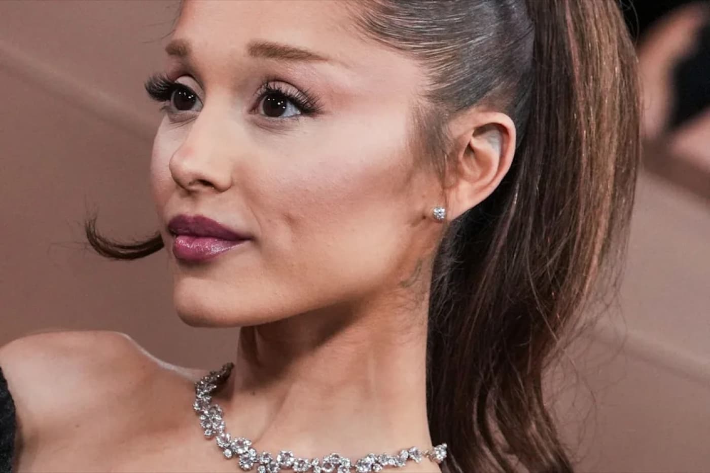 Ariana Grande in a close up portrait wearing a diamond necklace and her hair pulled back
