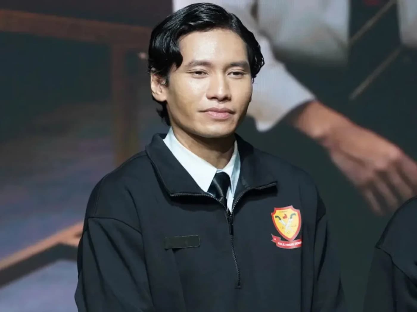 Dai Fuad on stage wearing a black jacket with a crest patch