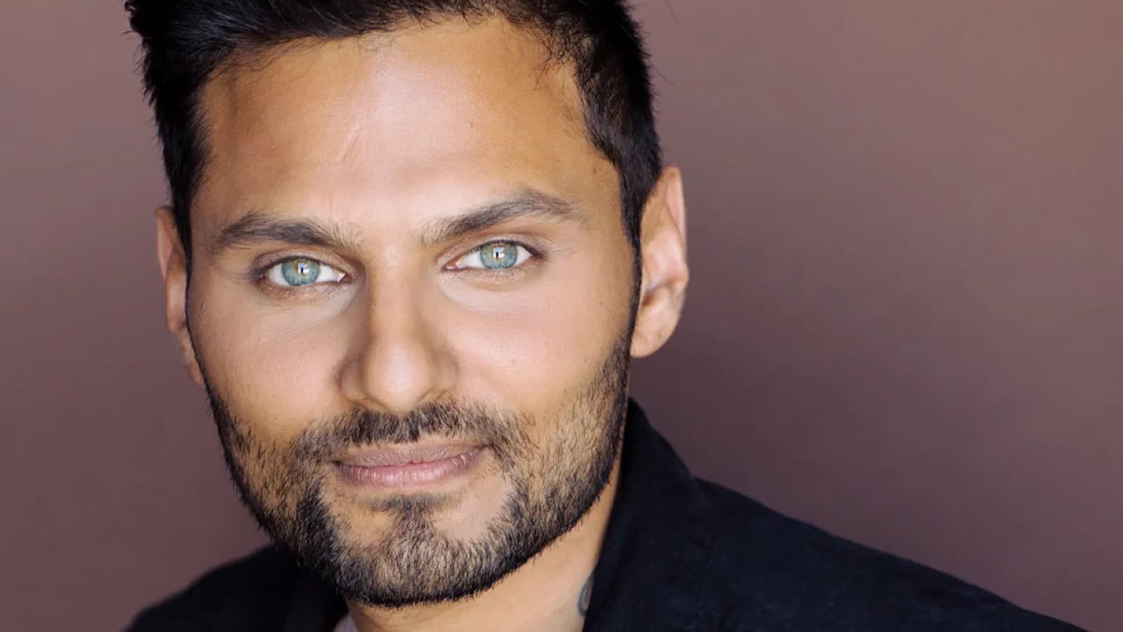 Close up portrait of Jay Shetty against a warm brown backdrop