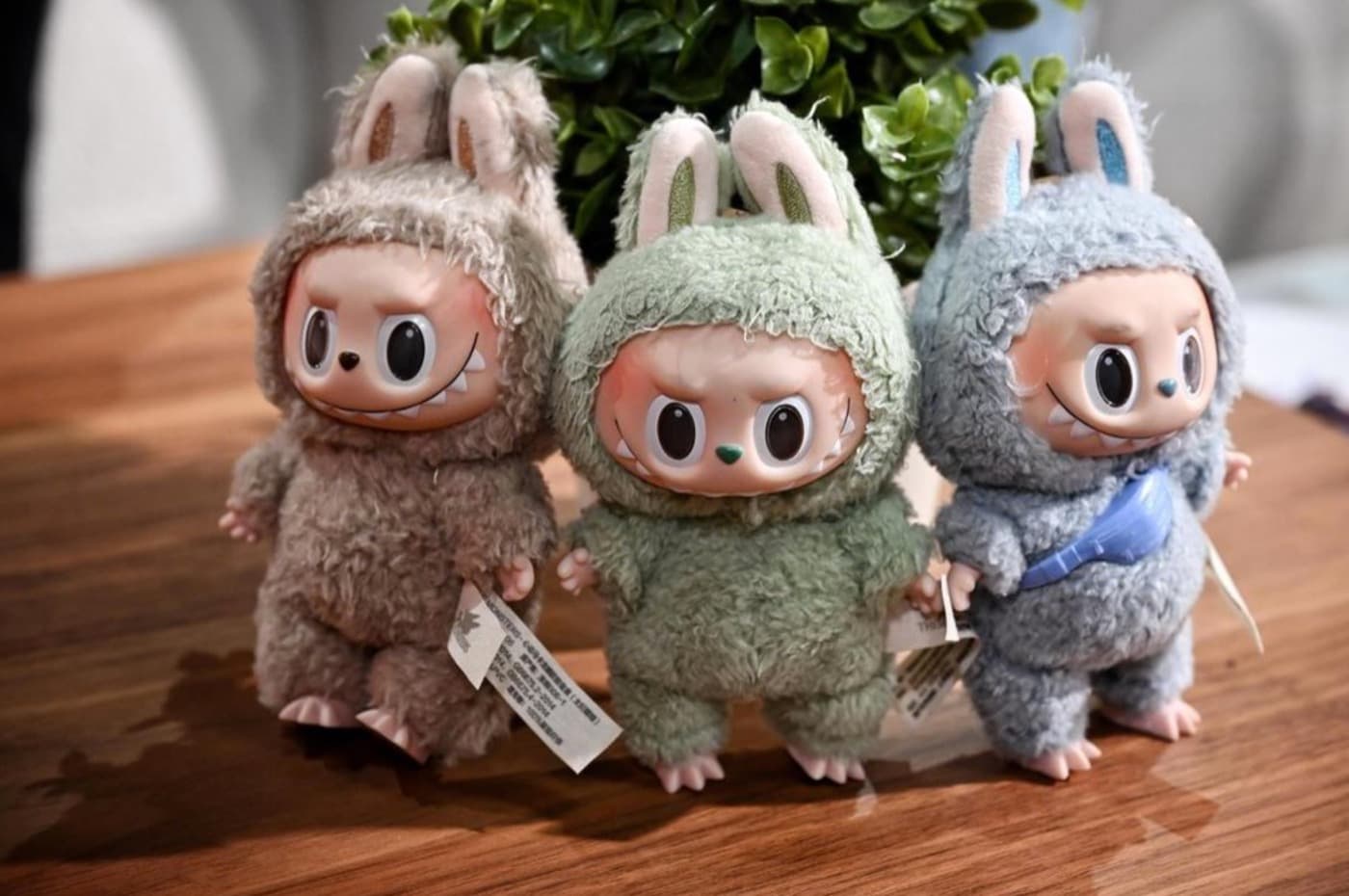 Three plush Labubu figures in animal costumes standing on a wooden table