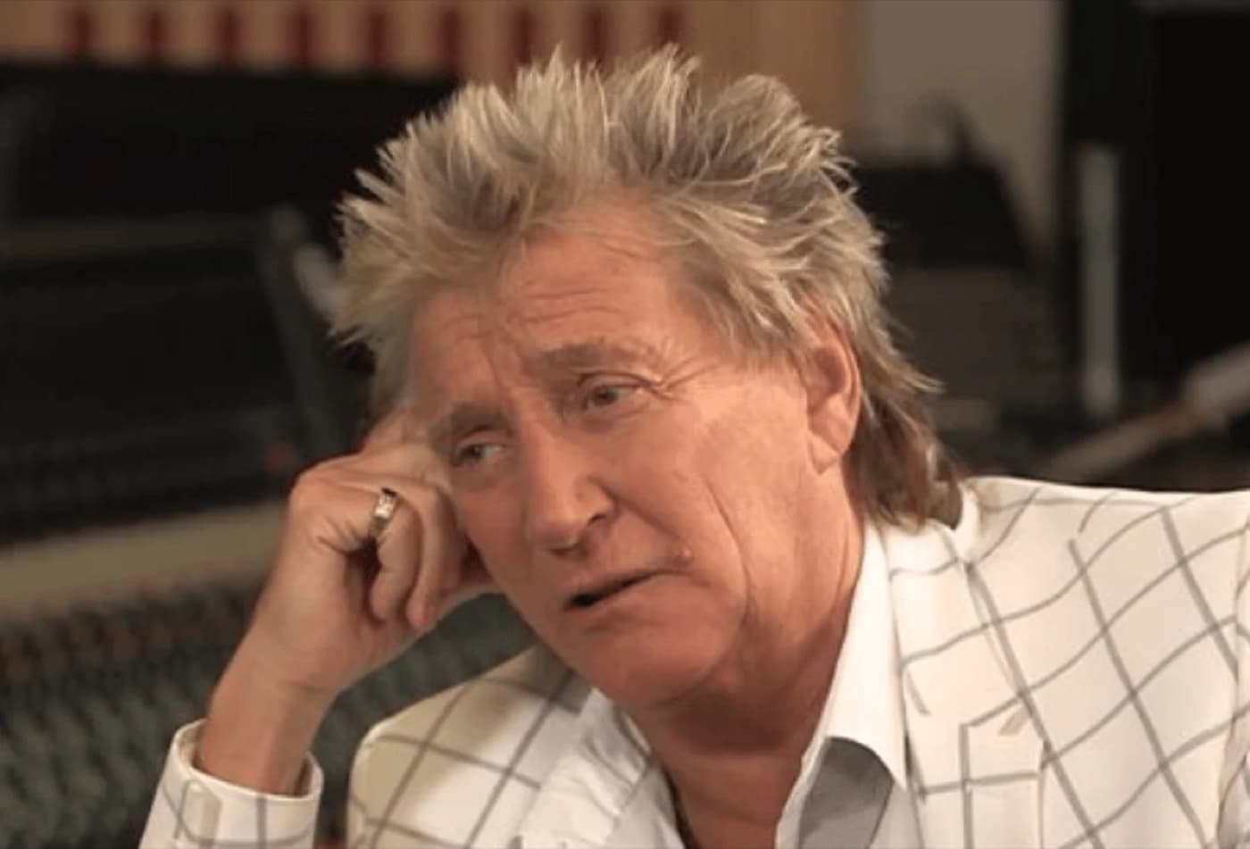 Rod Stewart resting his head on his hand in a studio setting