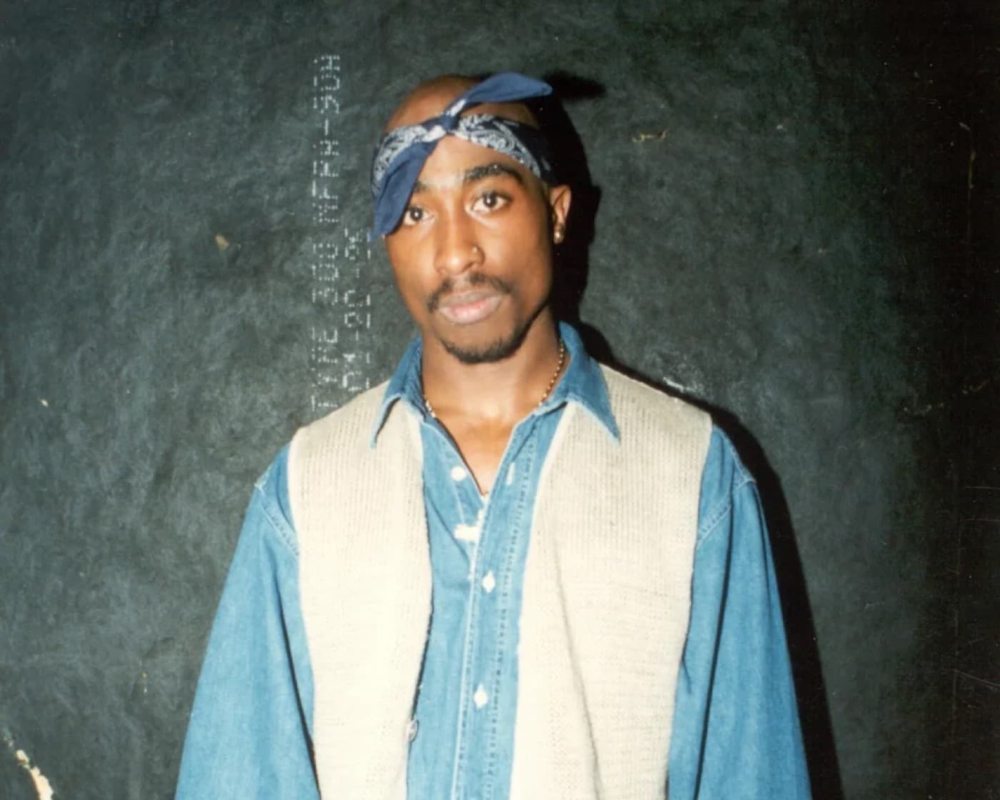 Tupac Shakur wearing a blue bandana and denim jacket in a portrait photo