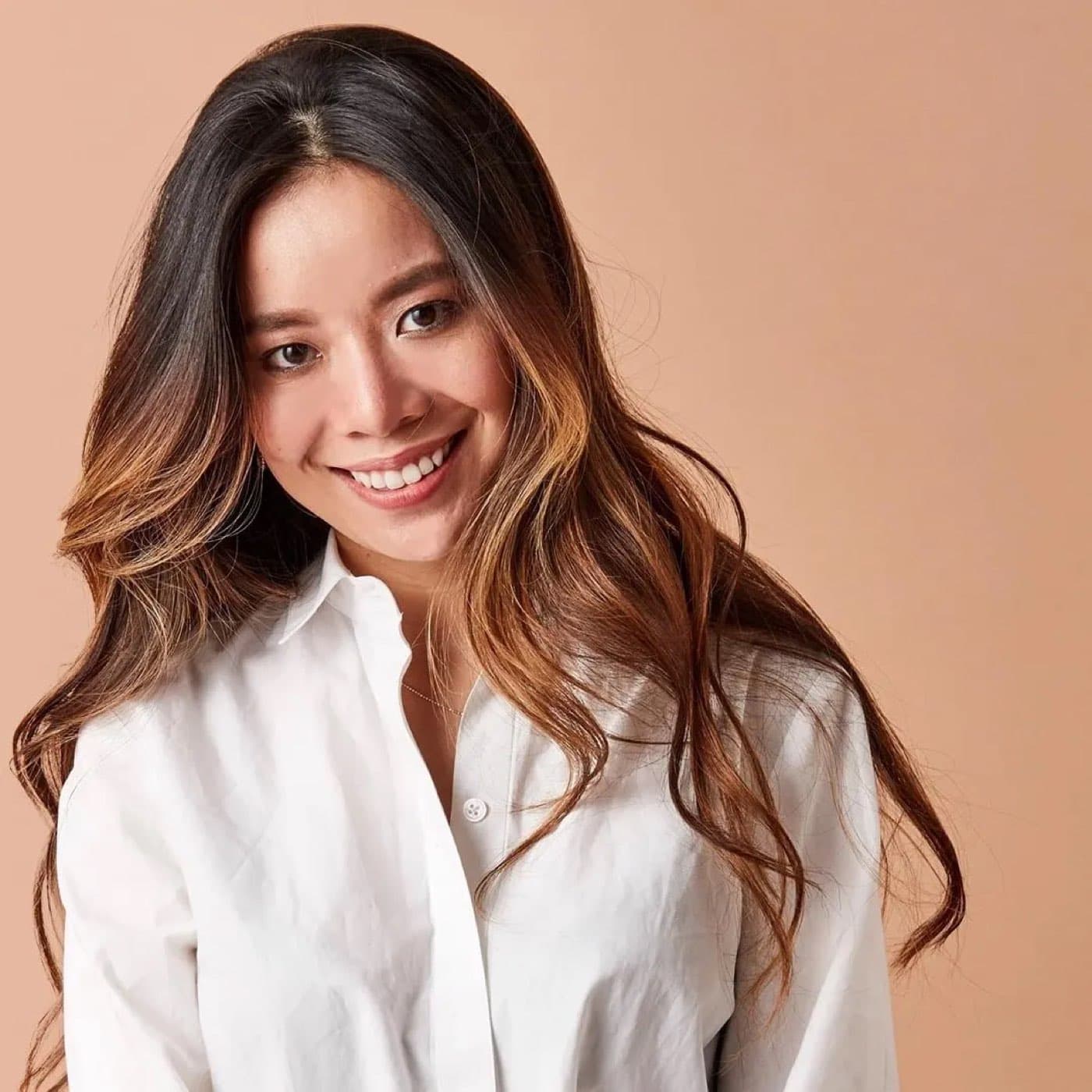 Kimberley Ho, founder of Evereden, smiling in a white shirt against a peach backdrop