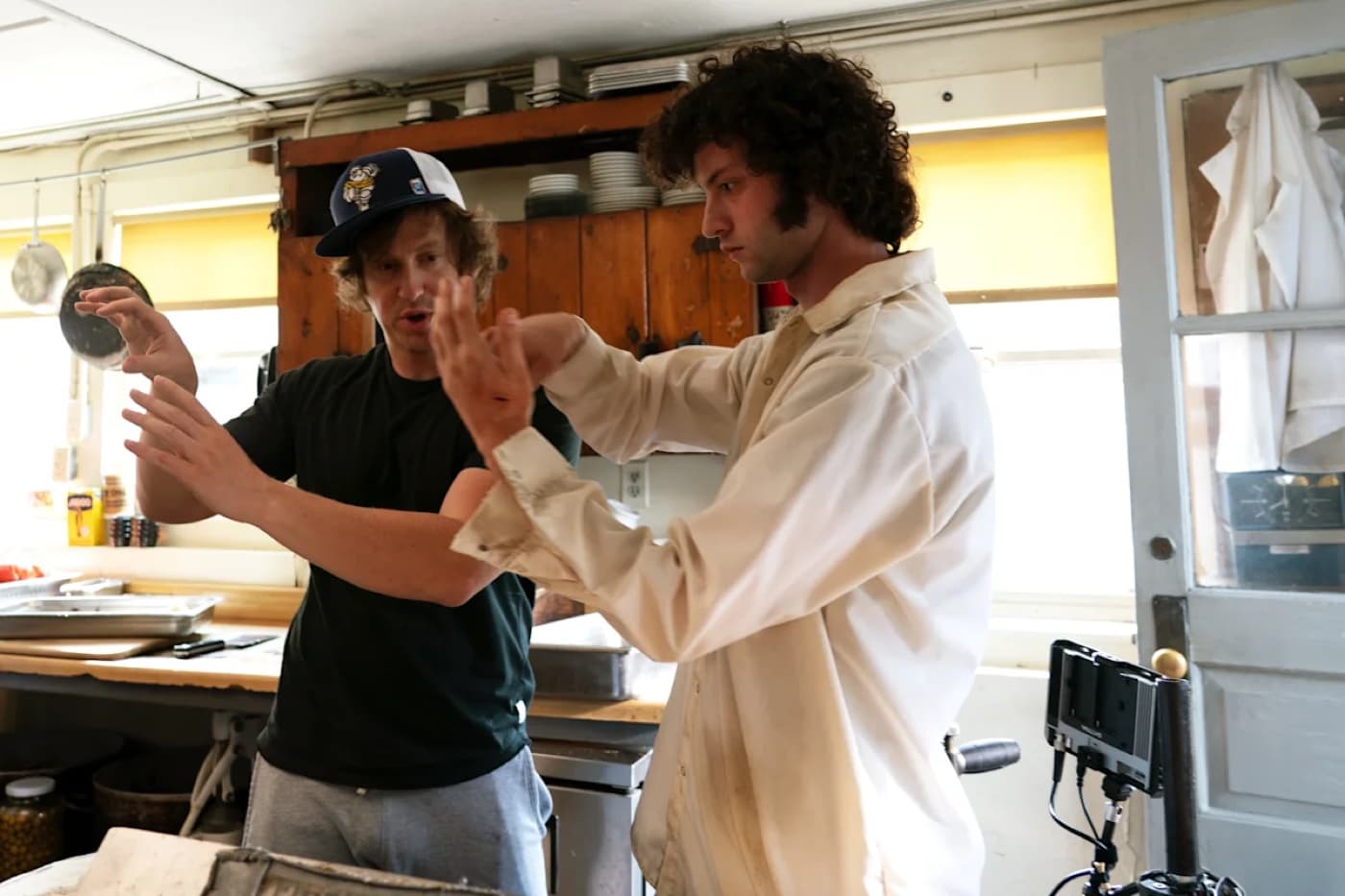 Matt Johnson and Dominic Sessa rehearsing a scene in a restaurant kitchen on the set of Tony