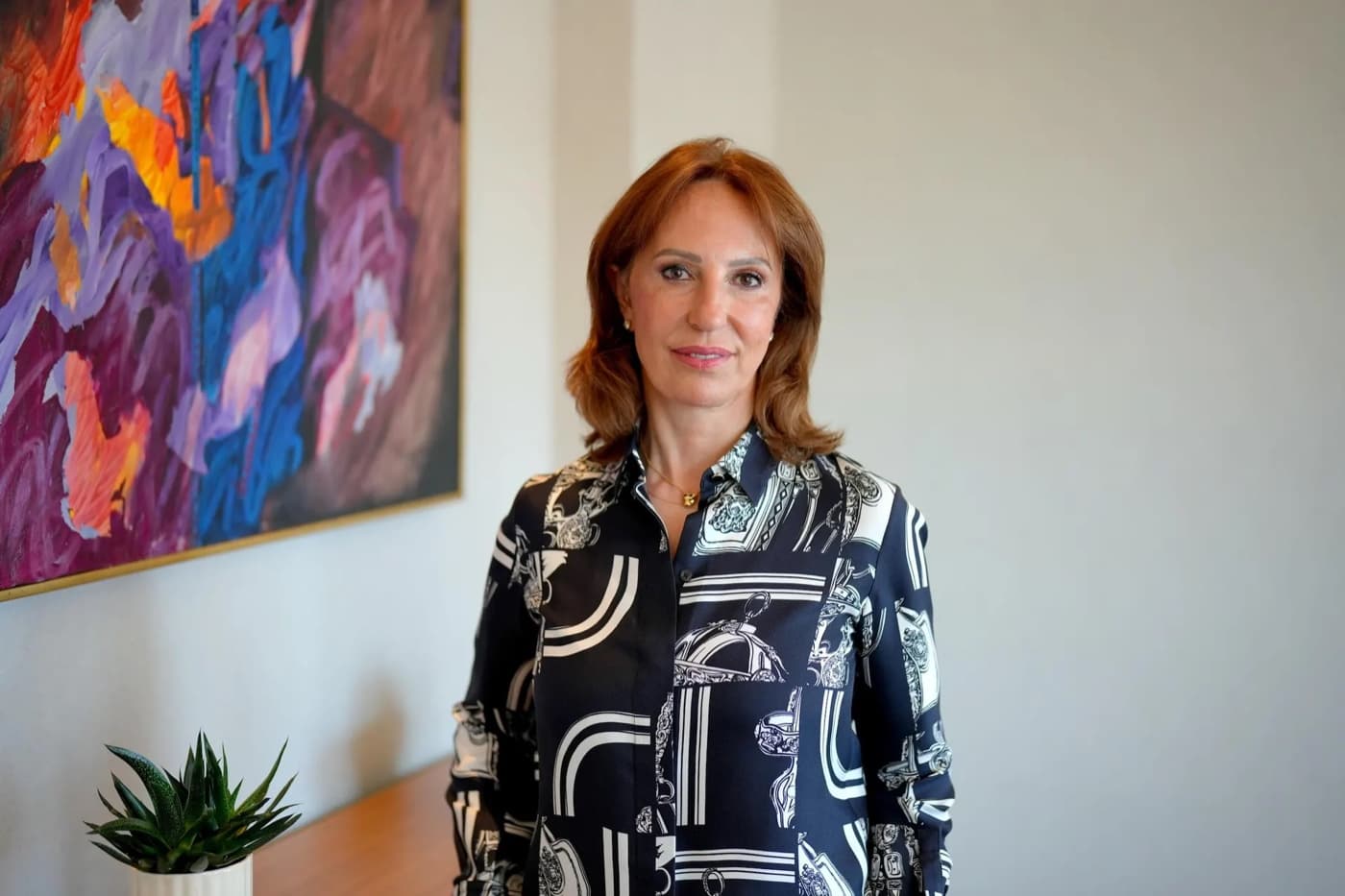Esin Gural Argat standing in front of a colorful abstract painting