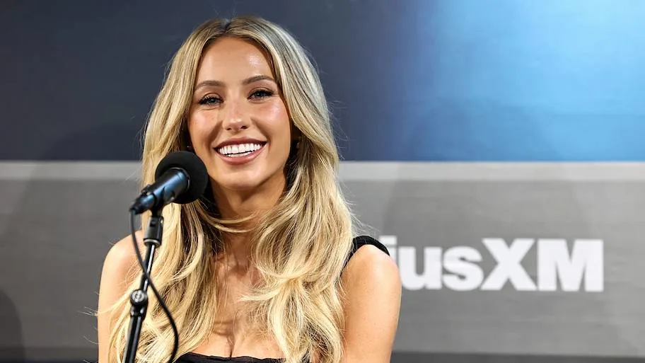 Alix Earle smiling while speaking into a microphone at an event