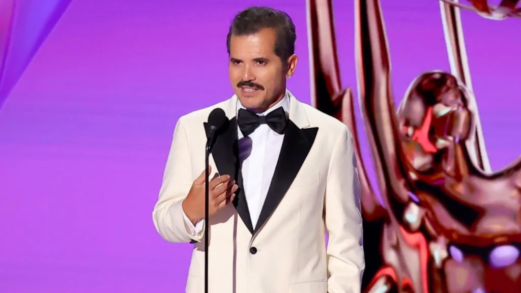 John Leguizamo speaking on stage at an awards ceremony